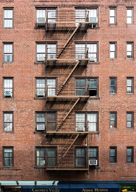 An interior staircase with narrow, steep steps painted in blue, showing signs of wear with chipped paint and scuff marks. The staircase includes a metal spiral banister with a wooden handrail, positio